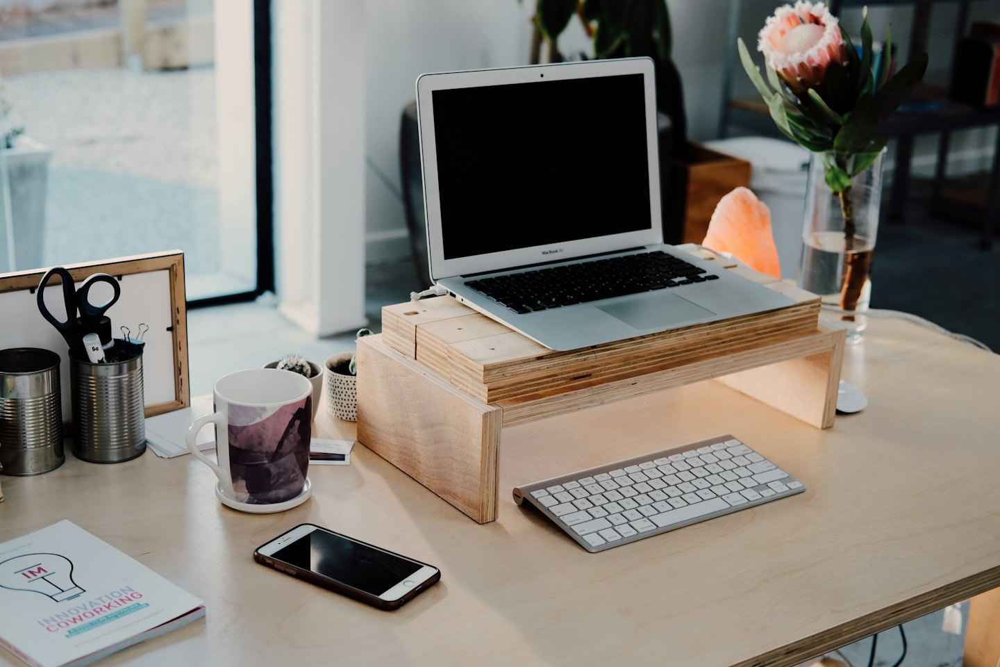 Modern wooden desk with laptop, keyboard, and succulents.